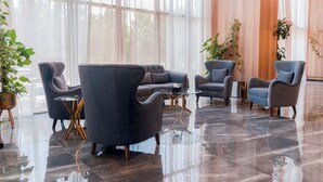 A spacious lobby with modern furniture, large windows, and a polished floor.