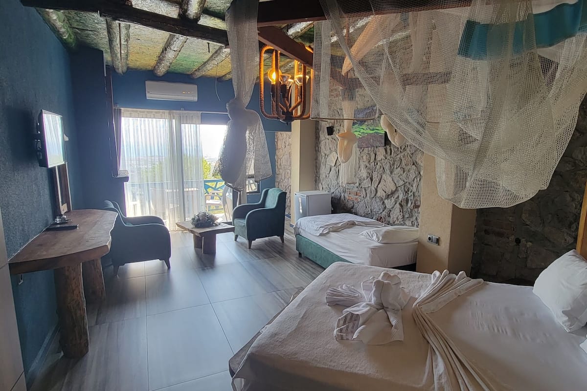 Ein Zimmer mit einem Bett, zwei Stühlen, einem kleinen Tisch und einem Fernseher.