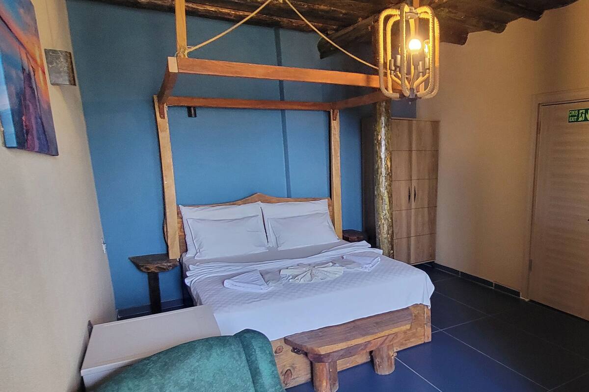 Ein Zimmer mit einem hölzernen Bett, einem grünen Sessel und einer blauen Wand.
