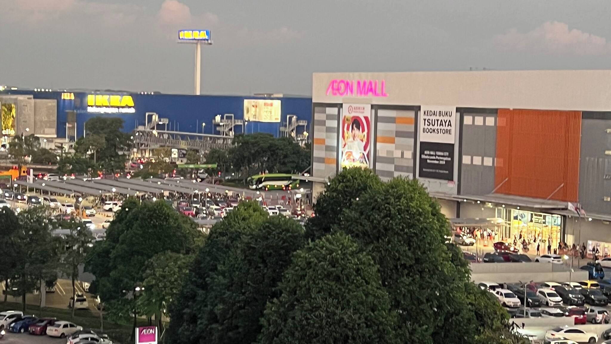 A busy urban scene with a large shopping mall, a highway, and a billboard.