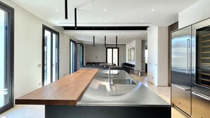 Une cuisine moderne dotée d’un îlot central, d’appareils électroménagers en acier inoxydable et d’un design minimaliste.