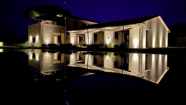 Une maison moderne dotée d’un grand patio, d’une piscine et offrant une vue sur un ciel nocturne dégagé.