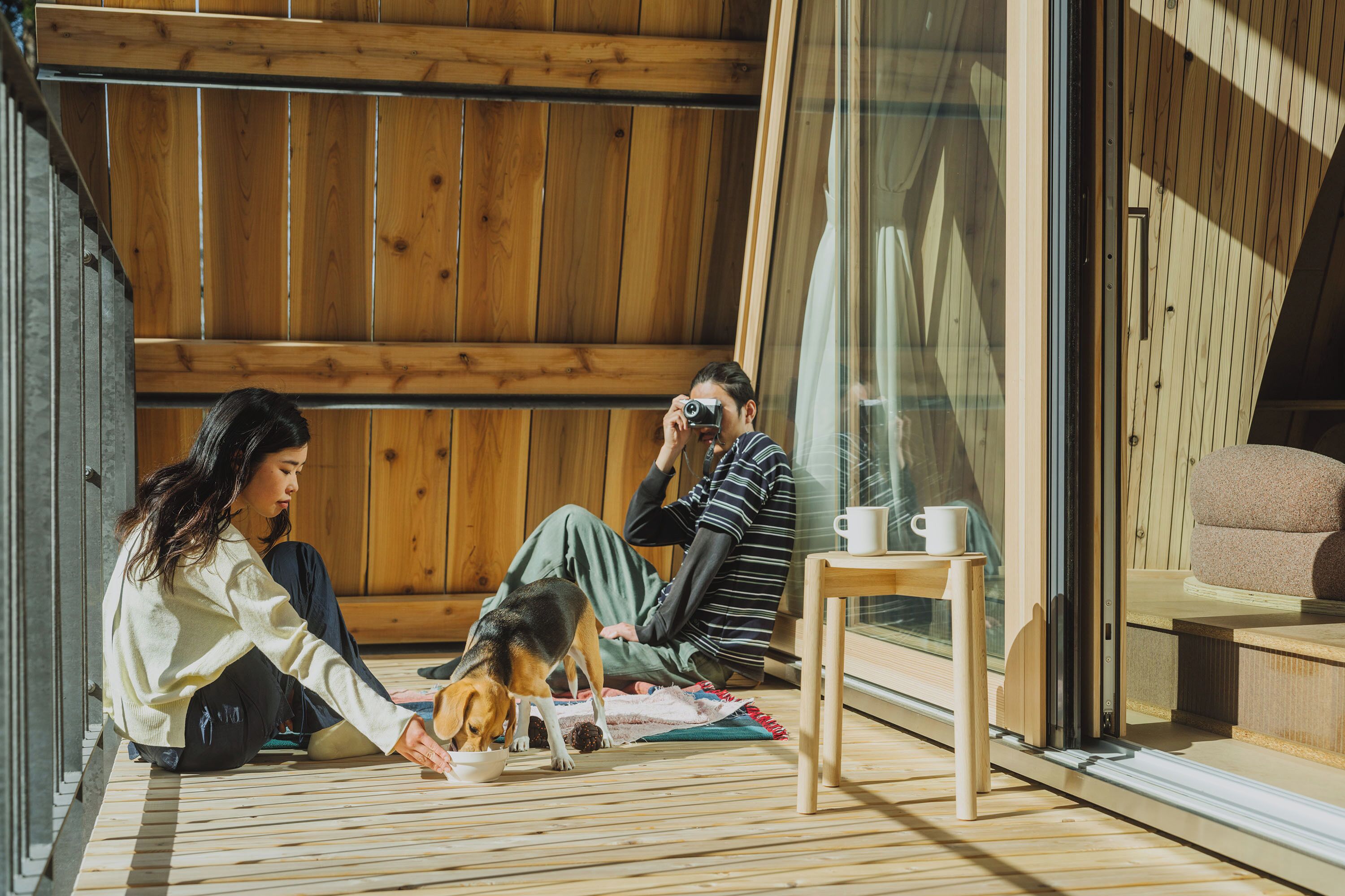 A cozy room with wooden flooring, a glass door, and a small table with a cup.