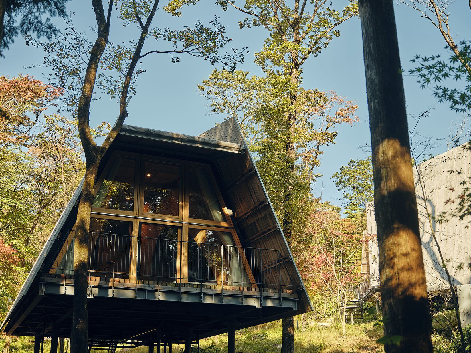 Una cabaña de madera con techo inclinado, ventanas amplias y un balcón.