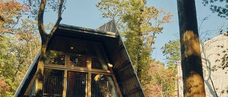 A wooden cabin with a sloped roof, large windows, and a balcony.
