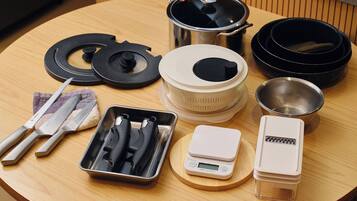 A kitchen counter with various cooking utensils, pots, and a digital scale.