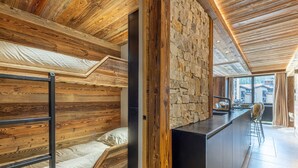 Ein modernes Interieur mit Etagenbett, Steinwand und Küchenbereich mit Bar.