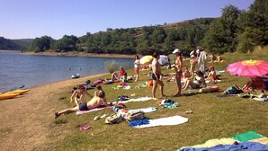 Une plage au bord d’un lac où des gens se prélassent au soleil et se baignent.