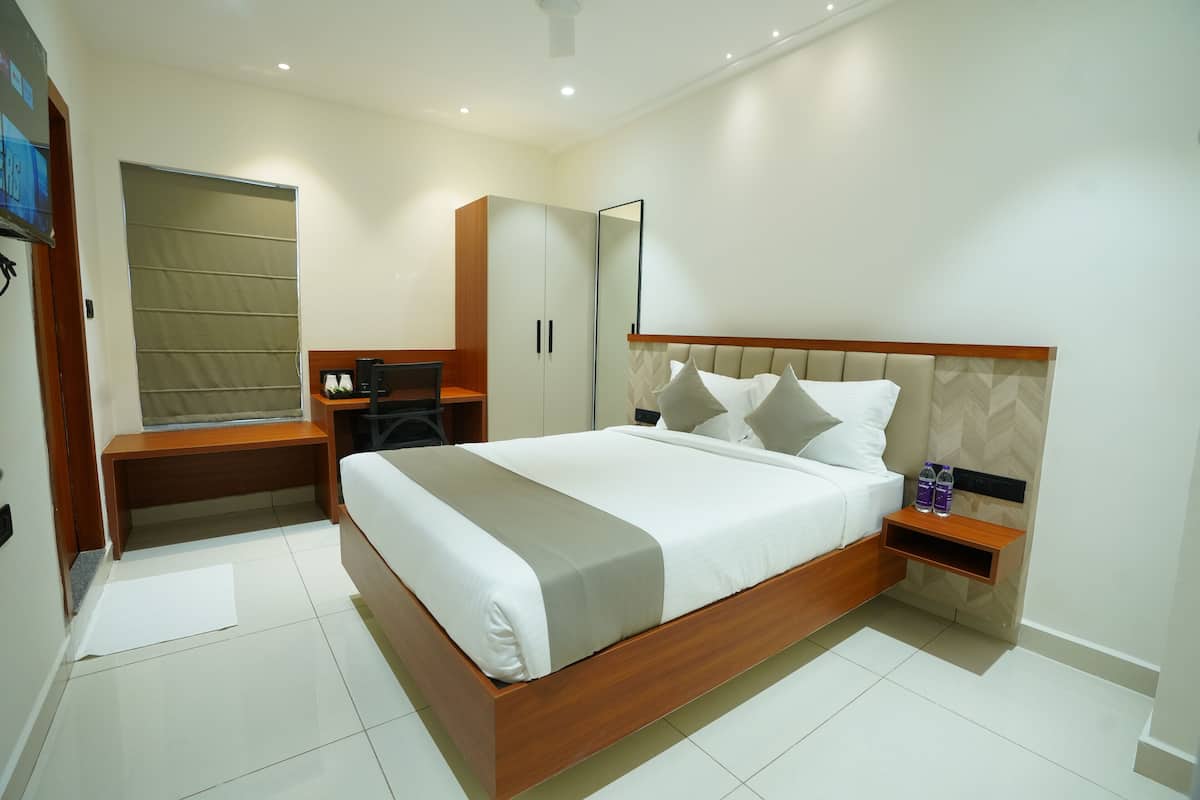 A modern bedroom with a large bed, a desk, a wardrobe, and a mirror.