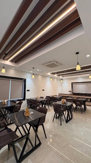 A modern conference room with multiple tables and chairs, wooden paneling on the ceiling, and pendant lighting. - LEONAR HOTEL (Hyderabad)