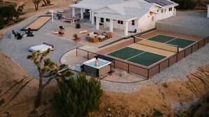 A modern house with a spacious patio, outdoor seating, and a hot tub. - Hoopa House by Fieldtrip - Pickleball + 2 Pools (Yucca Valley)