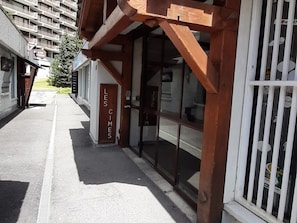 Un bâtiment doté d’une façade en bois, d’une entrée avec une porte en verre et d’une enseigne indiquant « LES CIMES ».