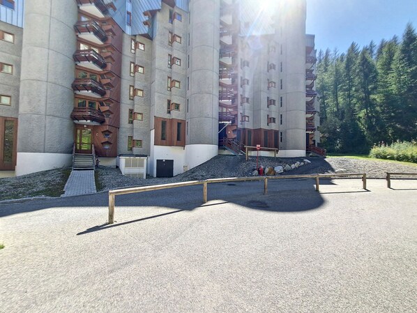 A modern multi-story building with a unique architectural design, featuring a combination of concrete and wood elements, and a central staircase leading to the entrance.