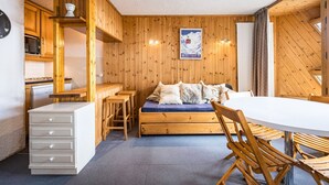 Una habitación acogedora con paredes de madera, una cama, una mesa de comedor y una zona de cocina.