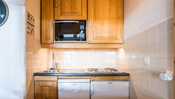Una cocina con armarios de madera, microondas, fregadero y lavavajillas.