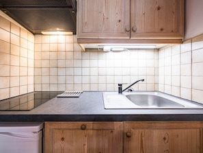 Cozinha com armários de madeira, pia de aço inoxidável e backsplash revestido de azulejos.