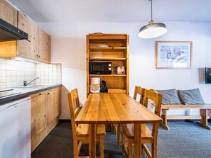 Uma cozinha compacta com armários de madeira, micro-ondas embutido e máquina de café.