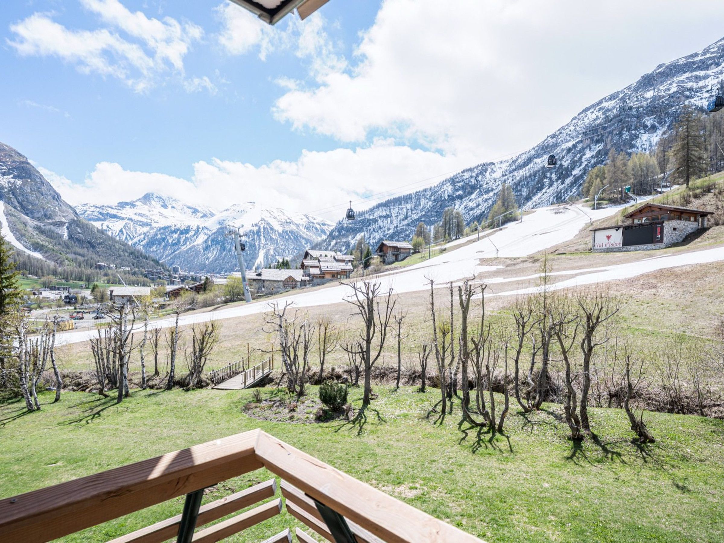 A mountainous landscape with a ski lift, a wooden bench, and a building with a sign.