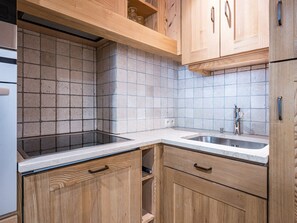 Une cuisine dotée d’un évier à deux bacs, de meubles en bois et d’un dosseret carrelé.