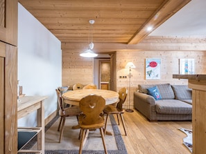 Un intérieur chaleureux en bois, avec une table ronde en bois, des chaises, un canapé et une lampe.