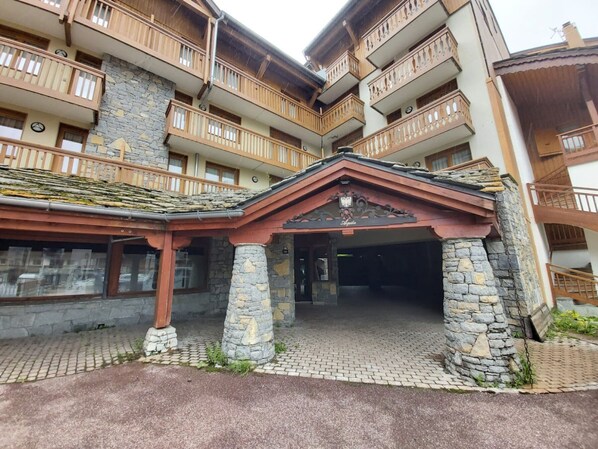 Un immeuble à plusieurs étages doté de balcons en bois, de piliers en pierre et d’un espace d’entrée abrité.