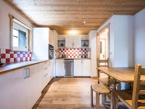 Una cocina con armarios de madera, lavavajillas de acero inoxidable y salpicadero de azulejos a cuadros.