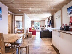 Ein Innenraum mit Holzboden, einer Essecke, einem roten Sofa und einer Küche mit Arbeitsplatte und Schränken.