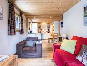 Una sala acogedora con un sofá marrón, un sofá rojo y un techo de madera.