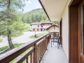 Ein Balkon mit Blick auf eine Berghütte, Holzgeländer und ein Steinhaus.