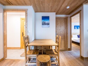 Ein Holzespeisesaal mit Stühlen, ein Gemälde an der Wand und ein Bett im angrenzenden Zimmer.