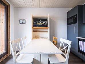 A modern kitchen with white cabinetry, a built-in microwave, and a large white table with chairs.