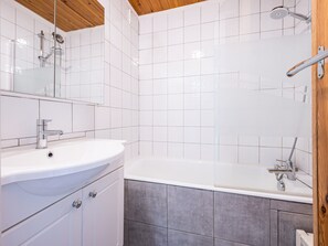 Une salle de bain avec un lavabo blanc, un miroir, une douche et une baignoire.