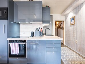 A modern kitchen with grey cabinets, a built-in oven, and a sink.