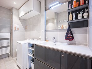 Un bagno moderno con un lavandino bianco, mobili scuri e uno specchio sopra il lavandino.