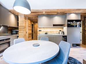 Uma cozinha moderna com detalhes em madeira, uma área de refeições com mesa redonda e um letreiro com a inscrição 'Mountain Collection'.