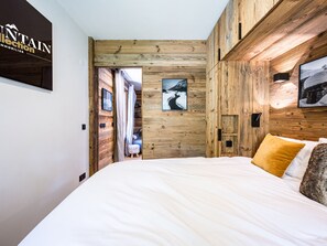Un dormitorio con pared de madera, una cama con ropa de cama blanca y un cuadro en la pared.