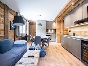 Eine moderne Küche mit Holzelementen, ein Essbereich mit einer Couch und Stühlen sowie eine sichtbare Kücheninsel.