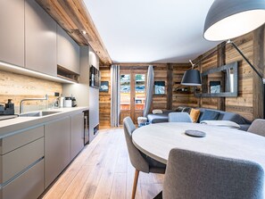A modern kitchen with a built-in stove, a dining area with a round table and chairs, and a cozy seating area with a sofa and a lamp.