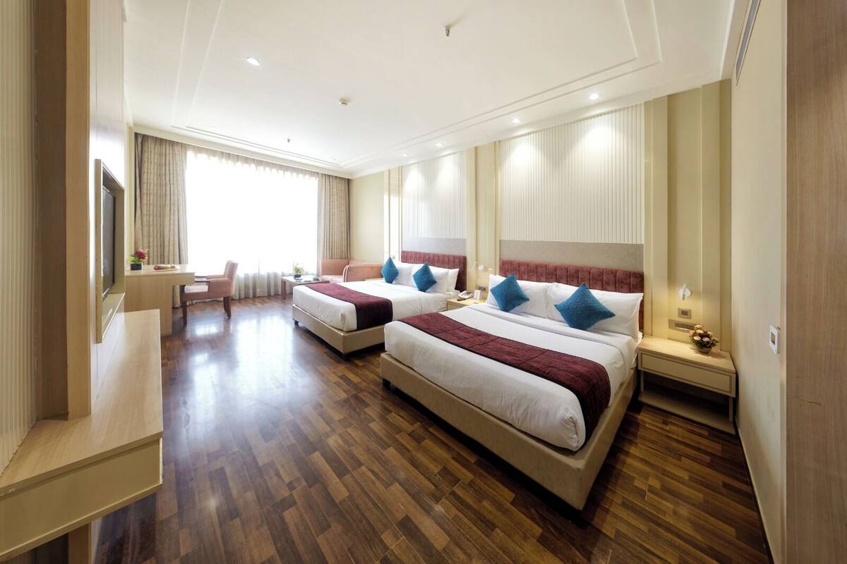 A hotel room with two beds, a desk, and a chair.