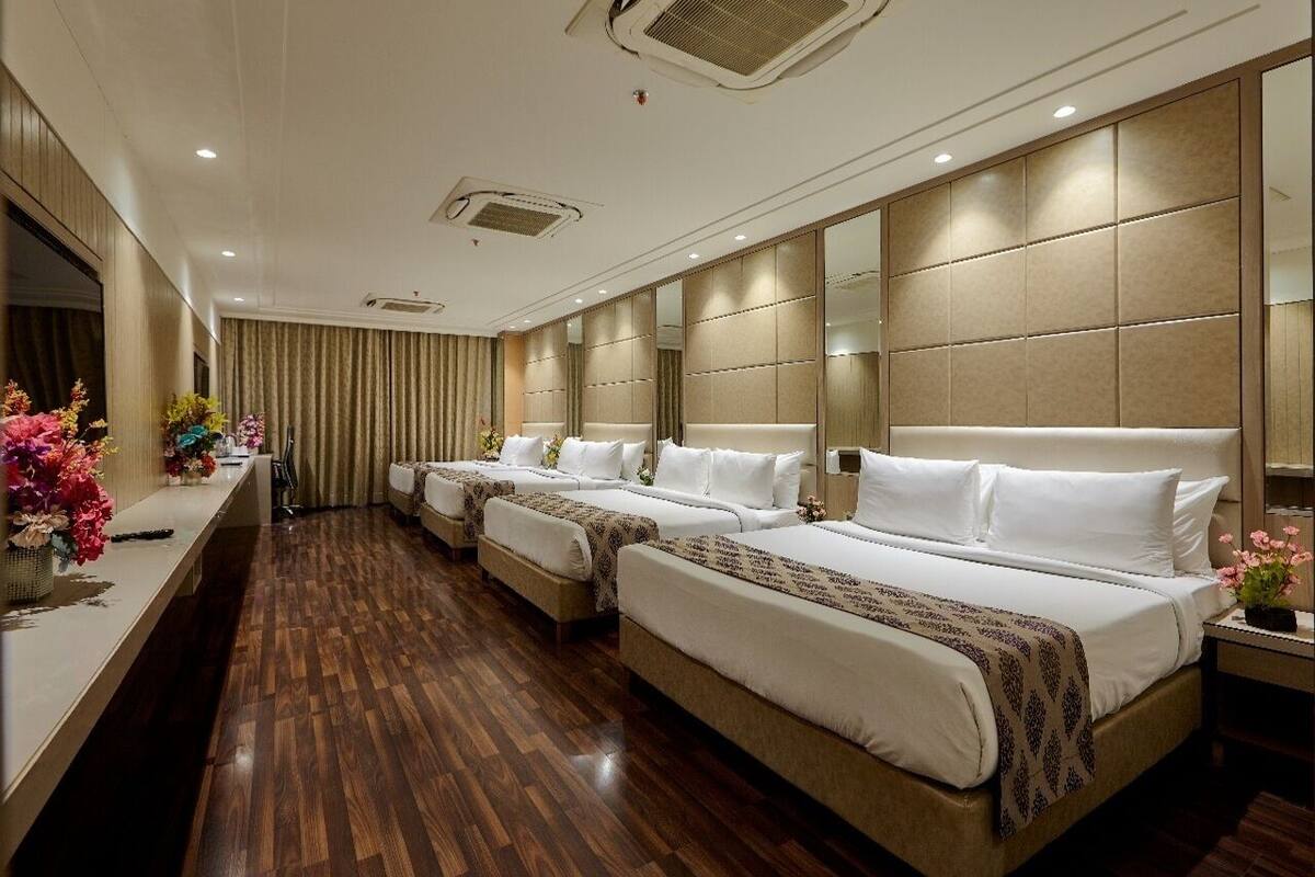 A hotel room with a large bed, a smaller bed, a vanity with a mirror, and a desk with a chair.