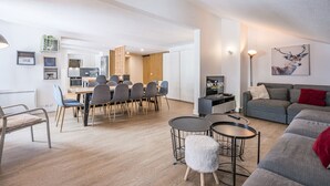 Een moderne woonkamer met een grijze bank, een salontafel en een eethoek met stoelen.