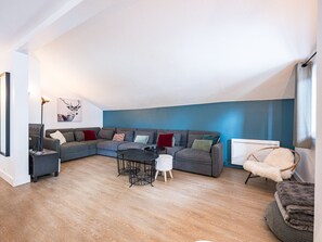 Una sala de estar moderna con un sofá modular, una mesita redonda, un sillón blanco mullido y un radiador.