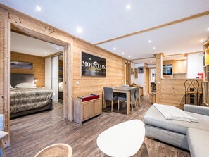 Un interior moderno con una cama, una zona de comedor, un sofá y una cocina visible a través de un arco.