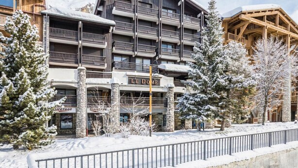 A multi-story hotel with balconies, stone pillars, and a sign reading 'Le Domaine.' - Luxury 3-room apartment, central location, parking included (Val-d'Isère)
