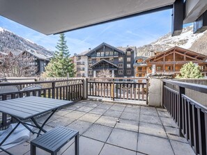 En balkong med utsikt över ett bergsområde med bland annat byggnader och träd.