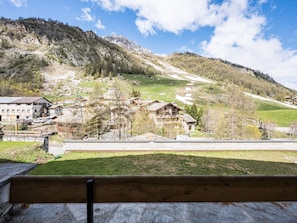 A mountain village with traditional wooden houses, a ski slope, and a clear sky.