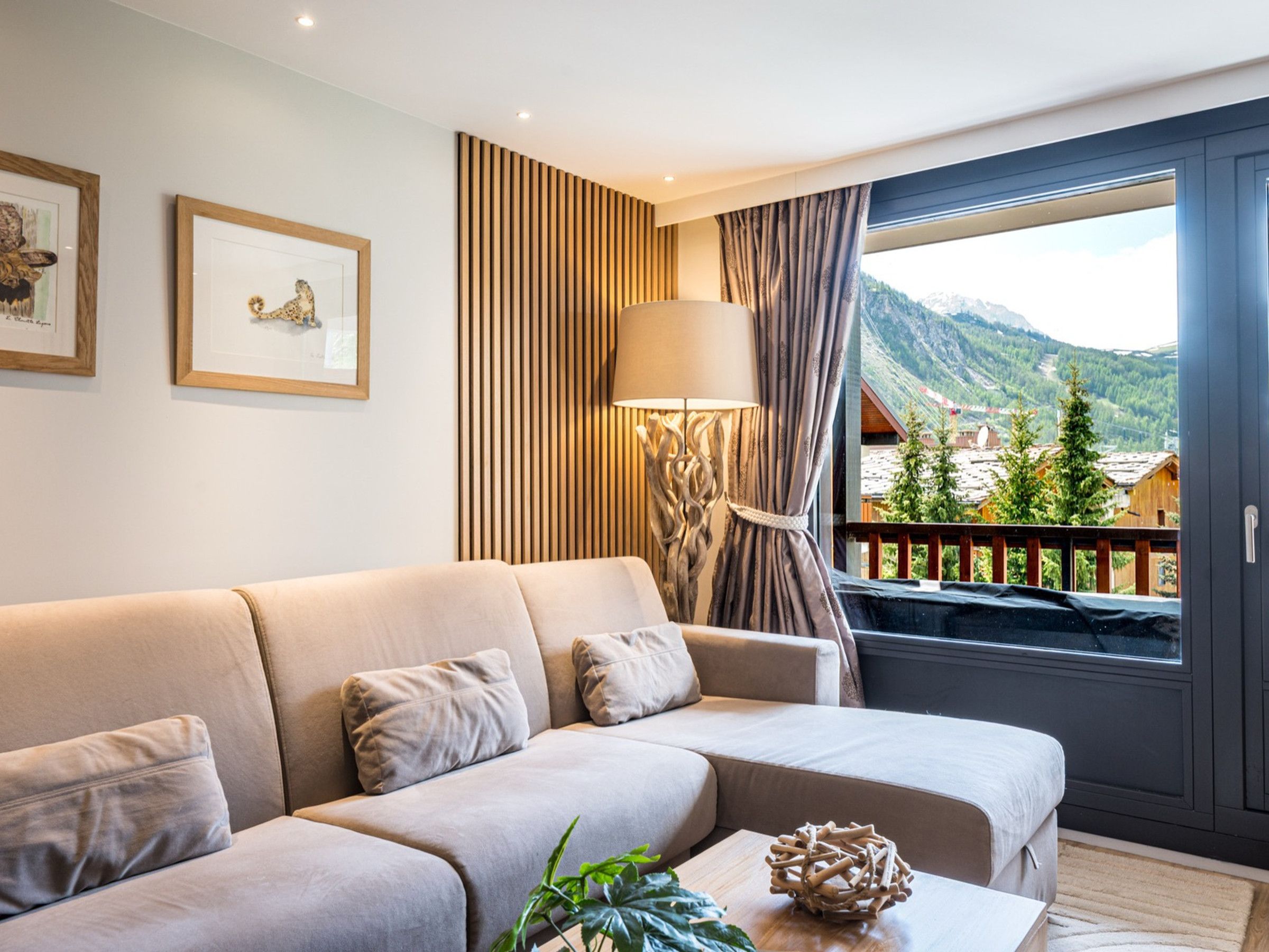 A modern living room with a sofa, a lamp, and a view of a mountain landscape.