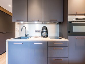 A modern kitchen with grey cabinets, a stainless steel sink, and a coffee maker. - Renovated studio Val-d'Isère center with balcony (Val-d'Isère)