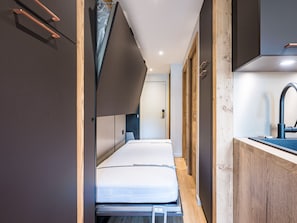 A compact room with a bed, a small kitchenette, and a bathroom.