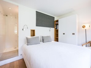 Una camera da letto con un letto, una doccia, una libreria e una lampada.